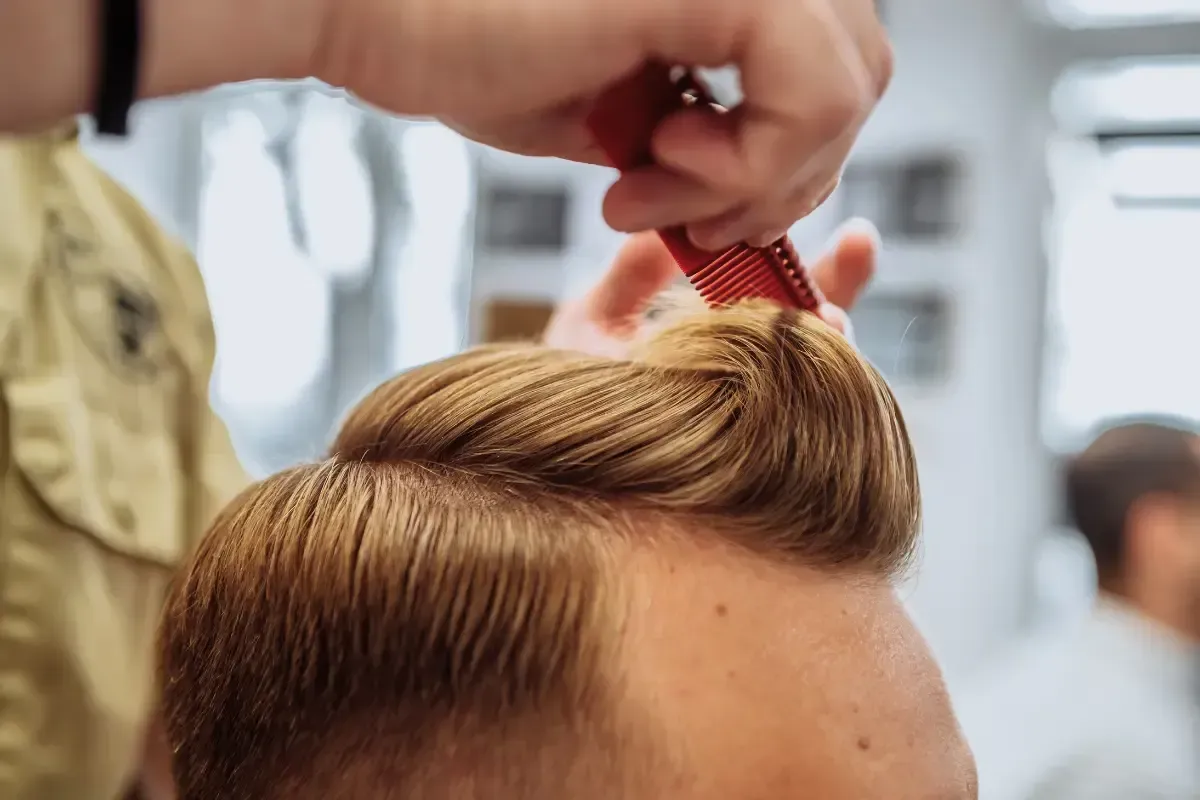 Barber styling a clean comb-over haircut with a red comb at Scuttlebutt Barbershop near Exeter, NH.
