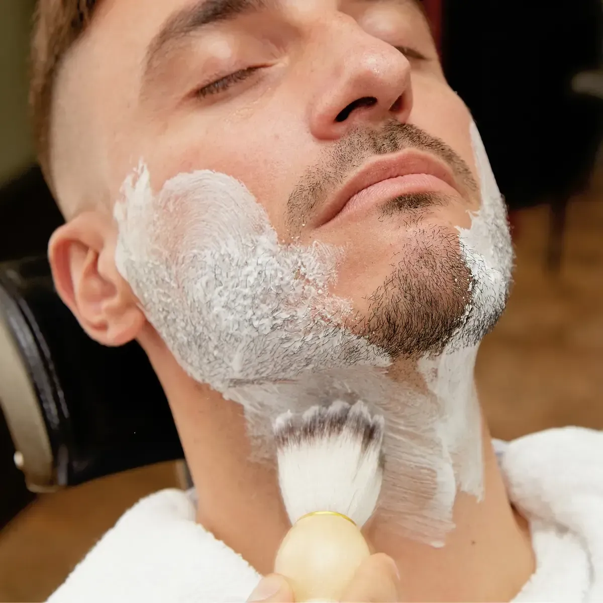 Close-up of a traditional straight razor shave at Scuttlebutt Barbershop in Portsmouth, NH, with lather applied to a client’s cheek.