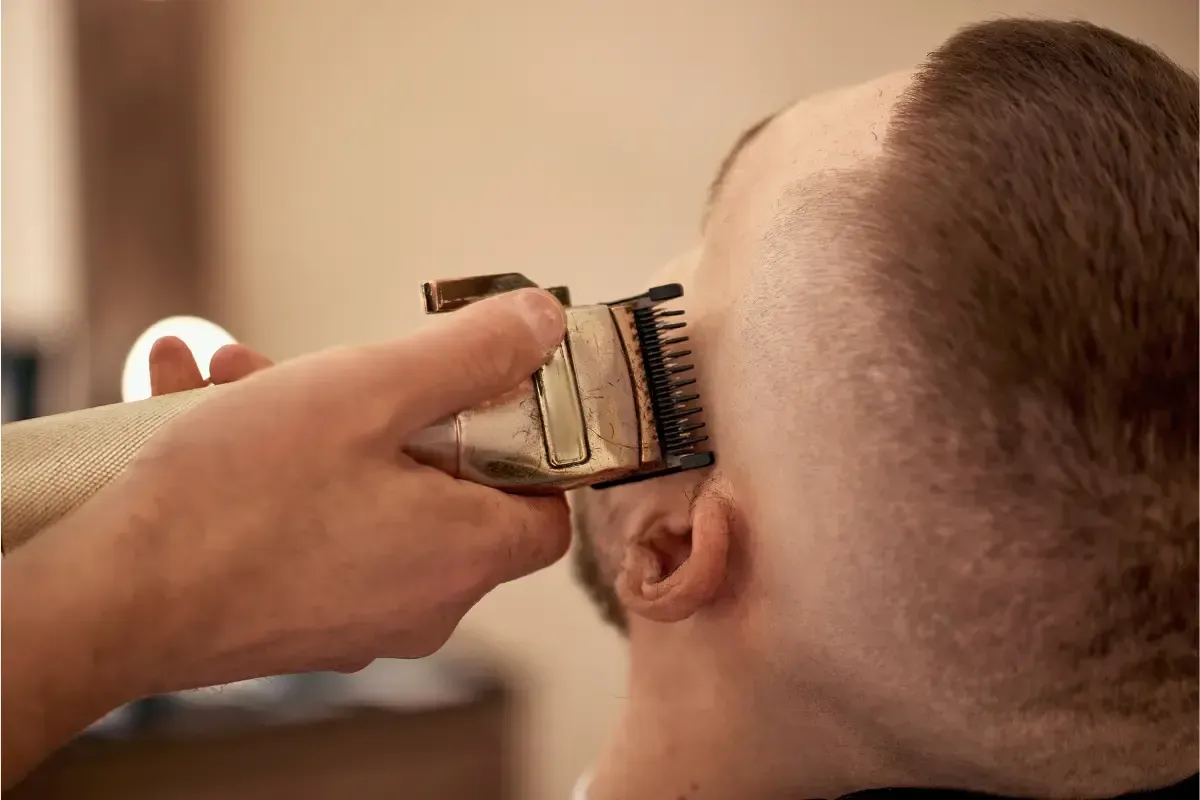 Close-up of barber using clippers to fade the side of a man’s haircut