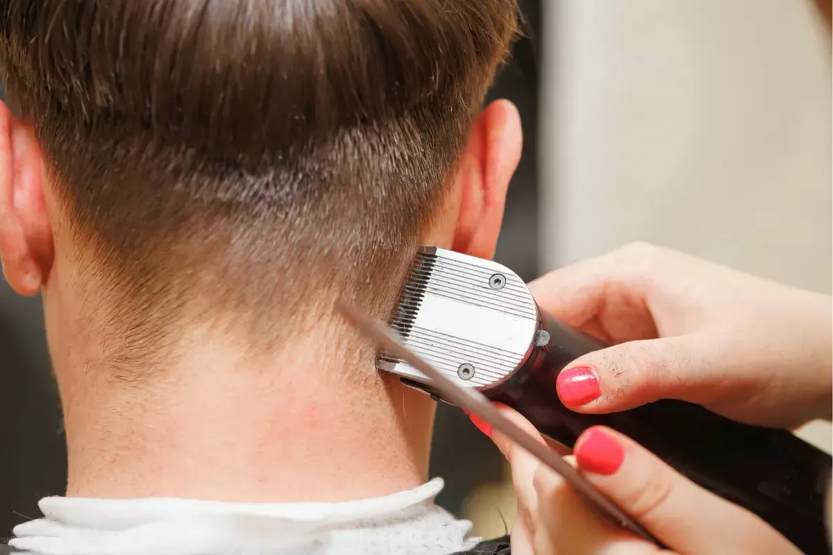 Barber using clippers to trim the back of a man’s haircut