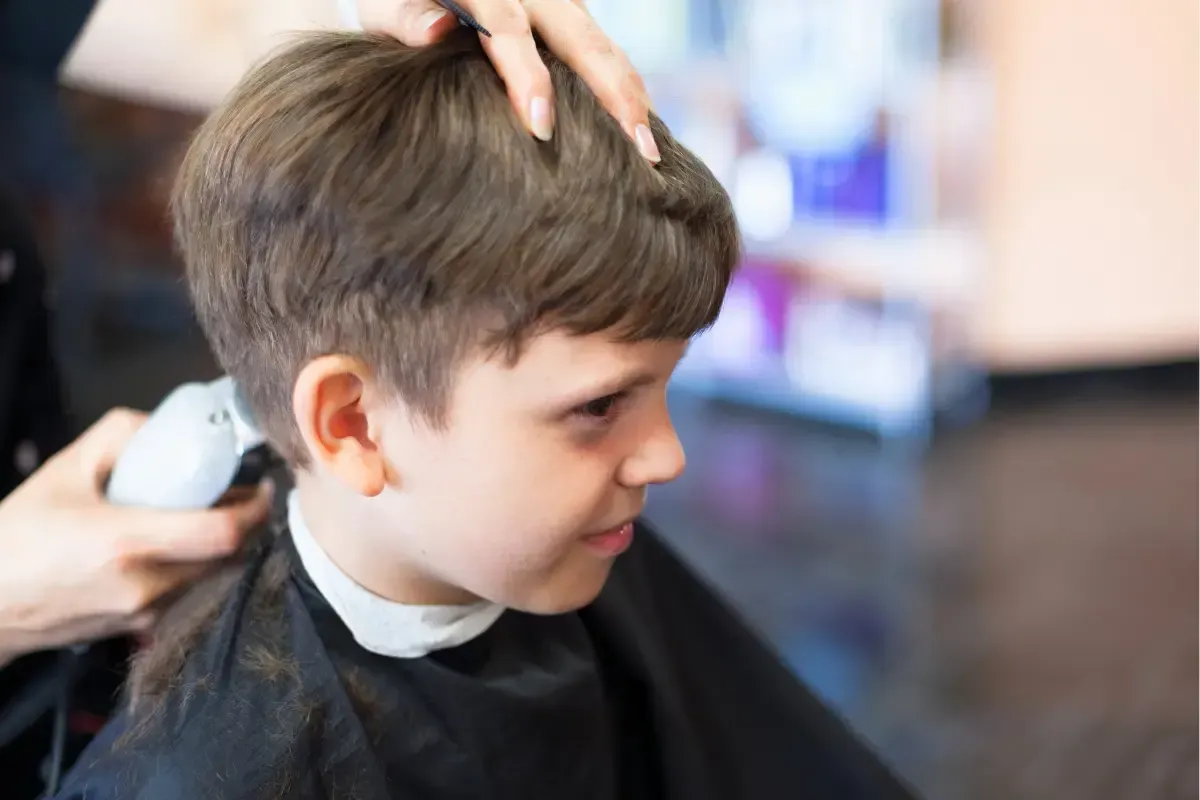 Young boy getting a haircut at a barbershop with clippers