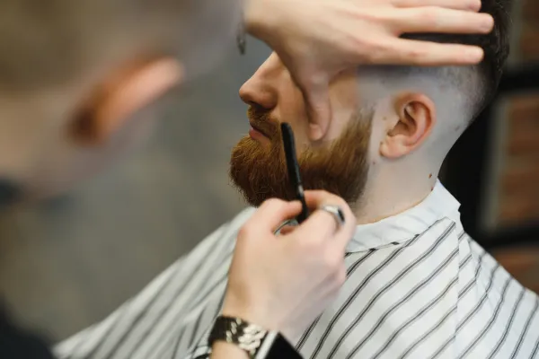 Barber shaping a man’s beard and haircut at Scuttlebutt Barbershop in Portsmouth NH