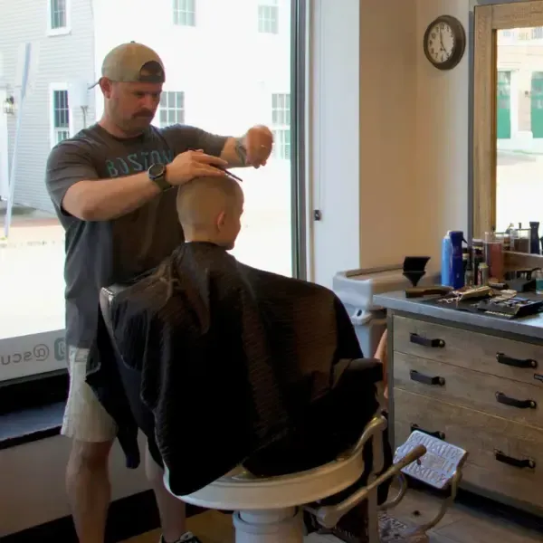 Barber giving a young boy a haircut in a barbershop chair