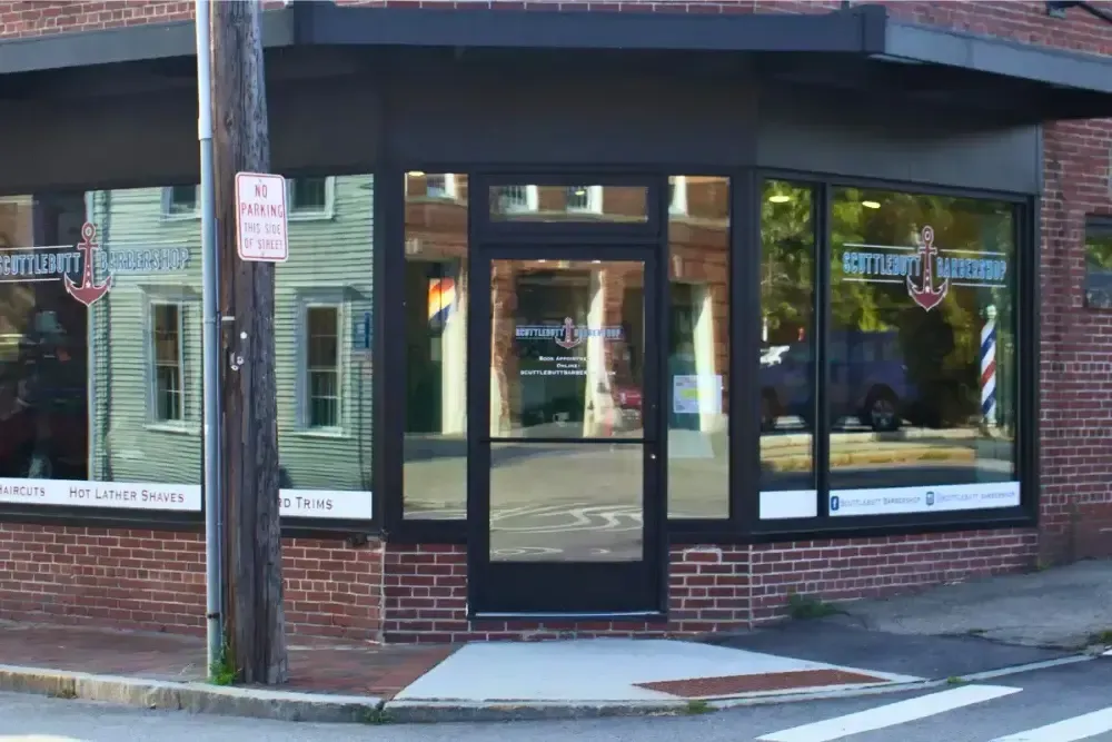 Front entrance of Scuttlebutt Barbershop in Portsmouth, NH with anchor logo on windows and door