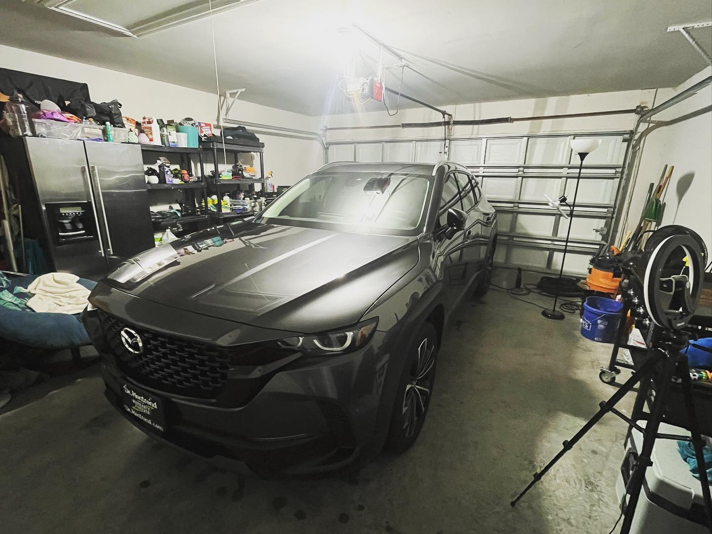 A professional car detailing team working on a modern vehicle in a clean garage — technicians are polishing paint and cleaning the interior, demonstrating precision and care.