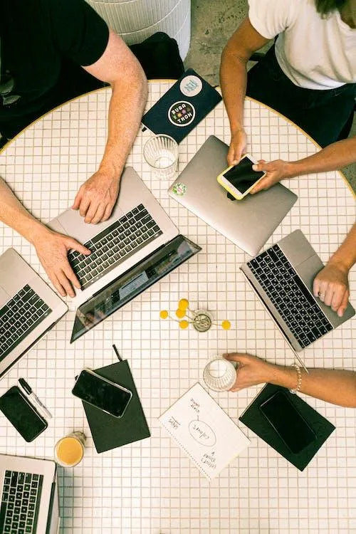 Circular table with individuals working on a strategy on their PC's