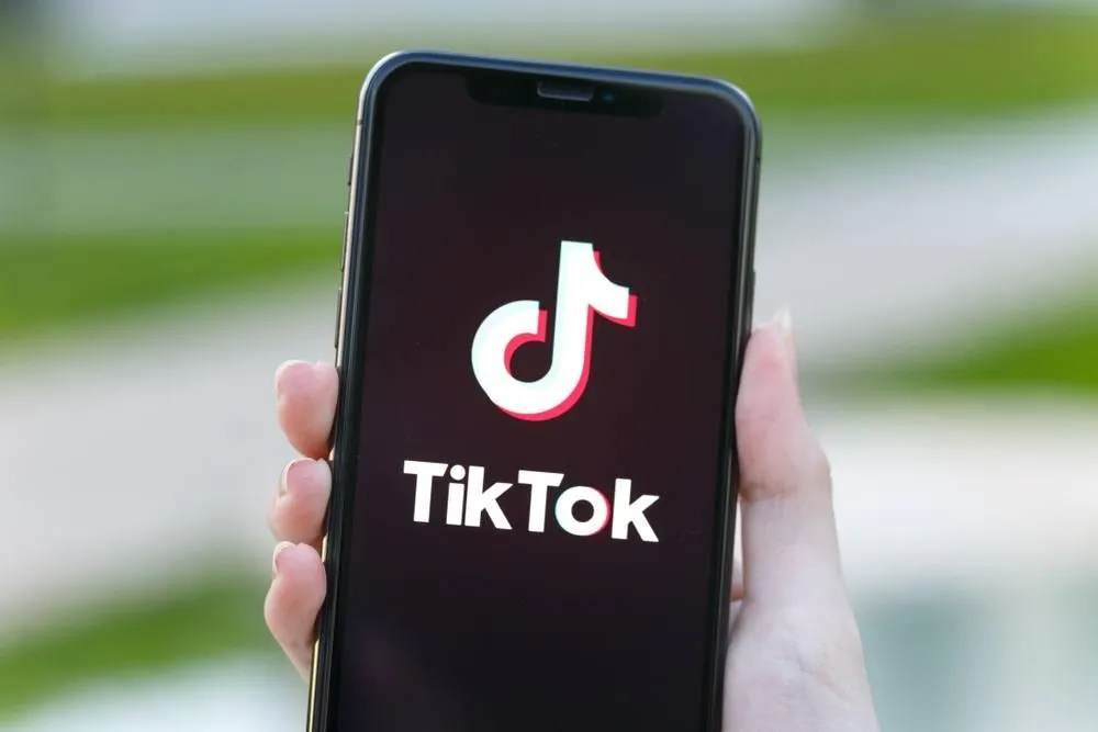 Hand holding a cell hone with the tiktok emblem