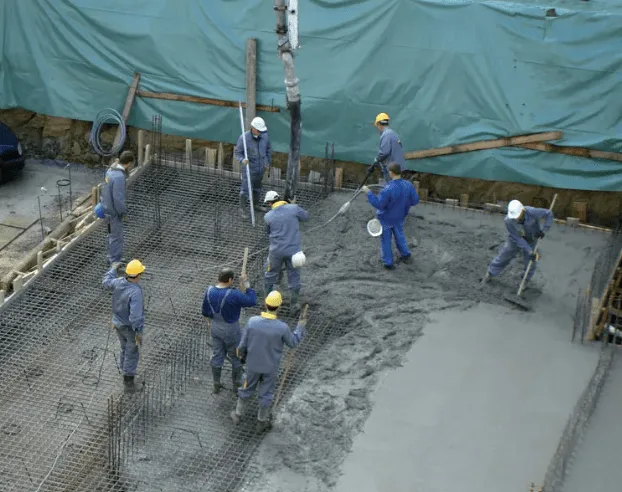 A team of concrete workers laying a structural foundation