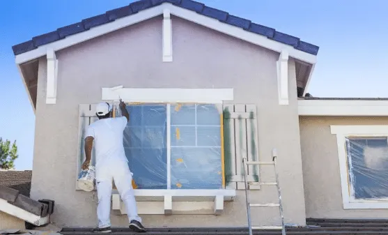 Man painting the exterior window frames of a home