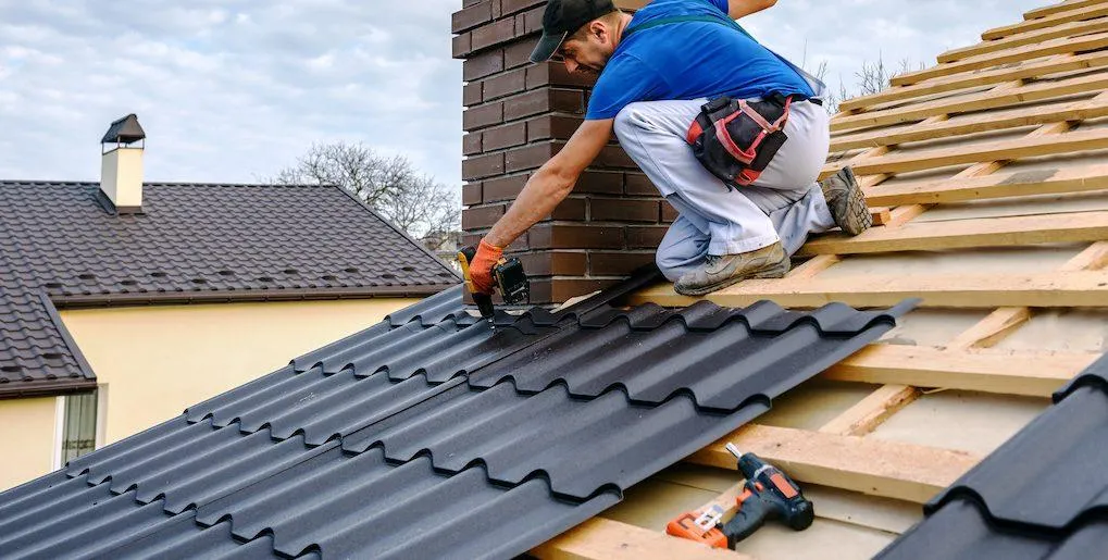 picture of a man near a chimney on a roof installing a metal roofing system.