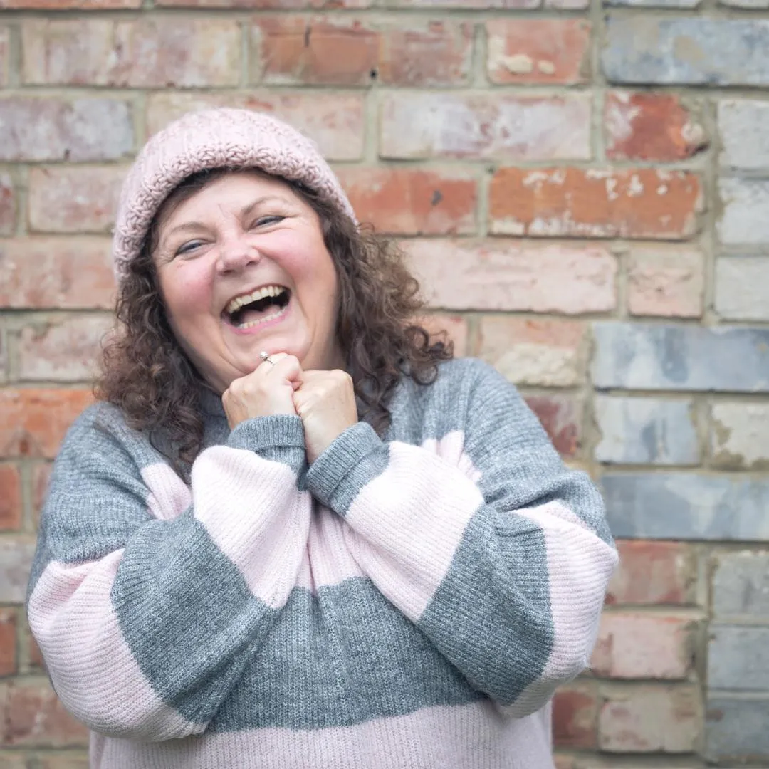 Becky Colwell laughing against a brick wall