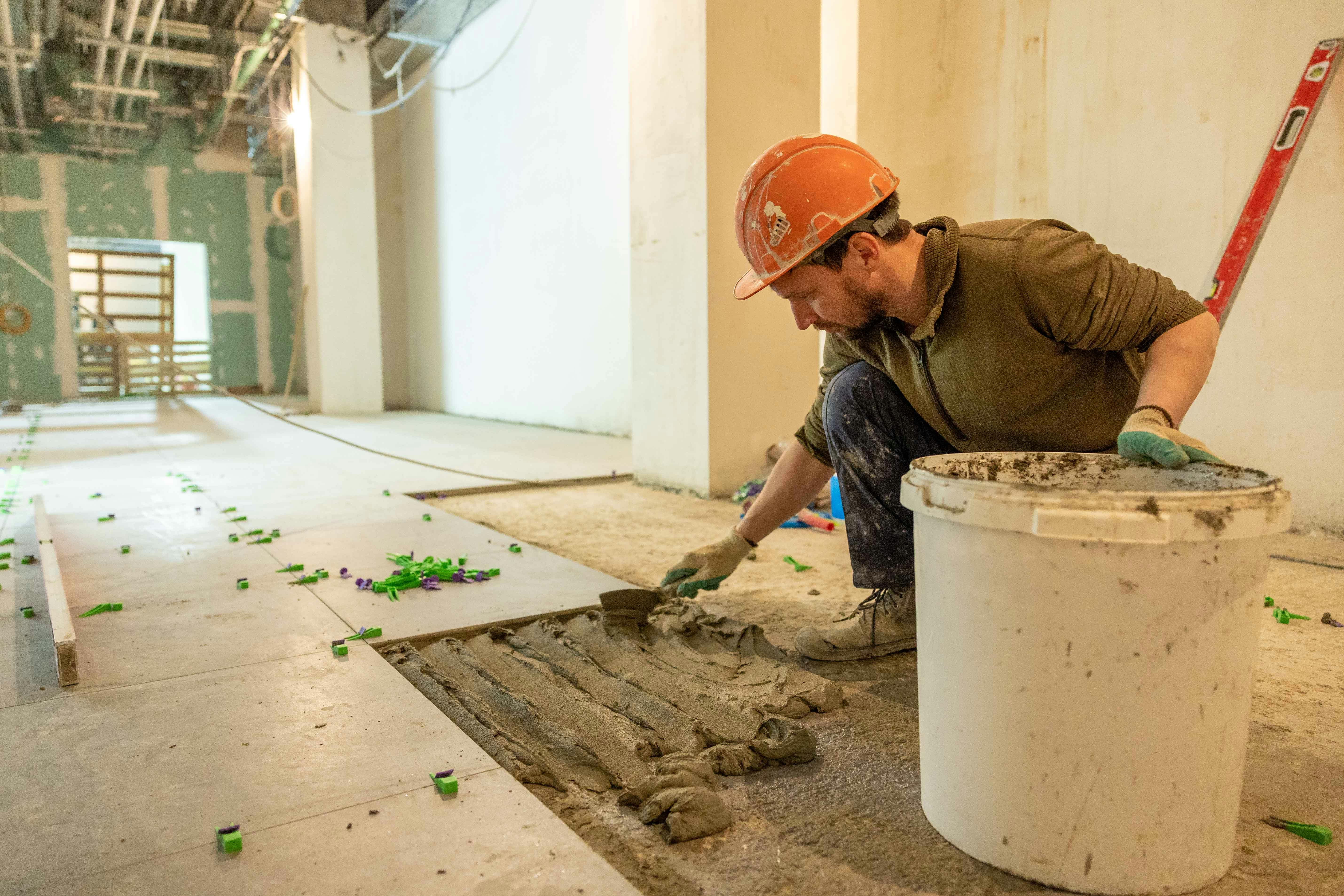 Basement development worker laying tiles