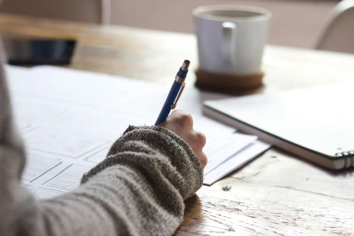 Thoughtful woman at desk with notebook and headphones