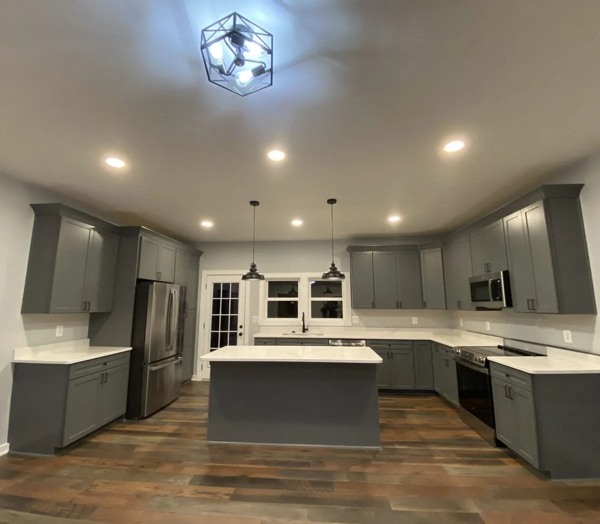 New kitchen with gray shaker cabinets, white countertops, island and stainless steel appliances