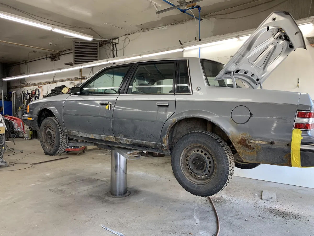 Voiture berline grise avec rouille visible et carrosserie endommagée en cours de réparation à l’atelier Centre Auto Loretteville.