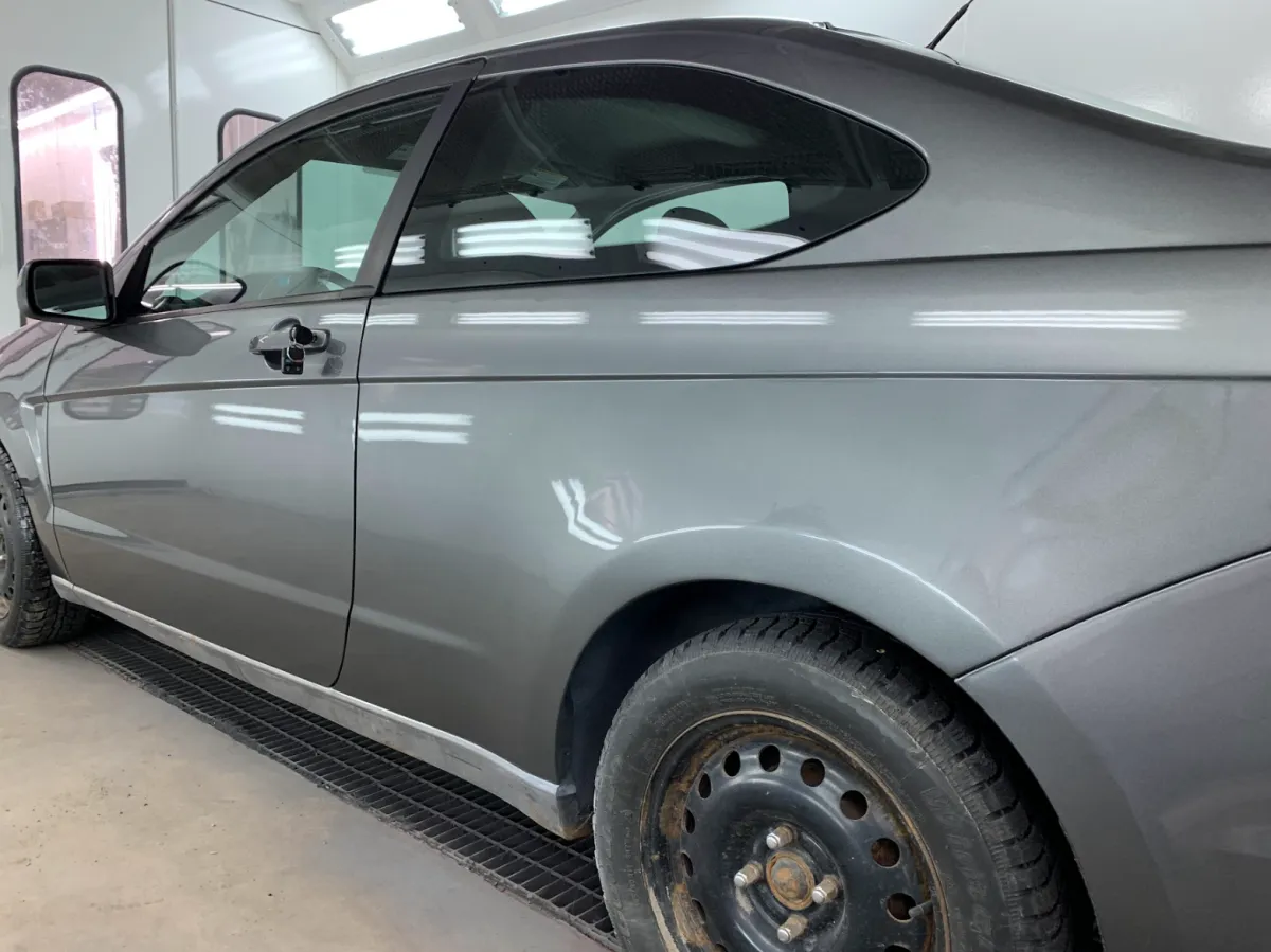 Carrosserie restaurée sur une voiture grise, finition lisse et sans défaut après débosselage et retouche en cabine de peinture.