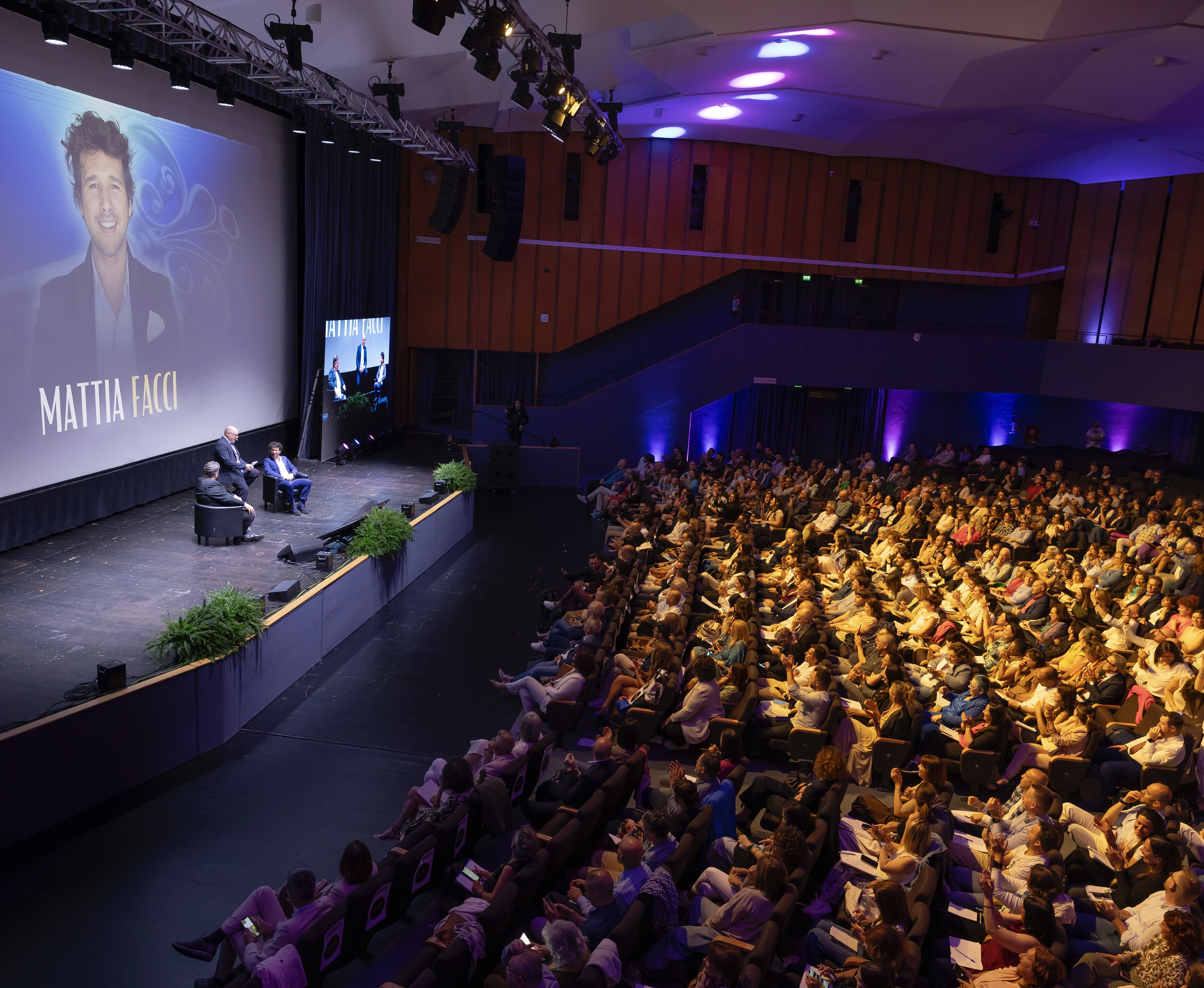 Collaborative workshop: three entrepreneurs around a glass table, city-view office, candid discussion