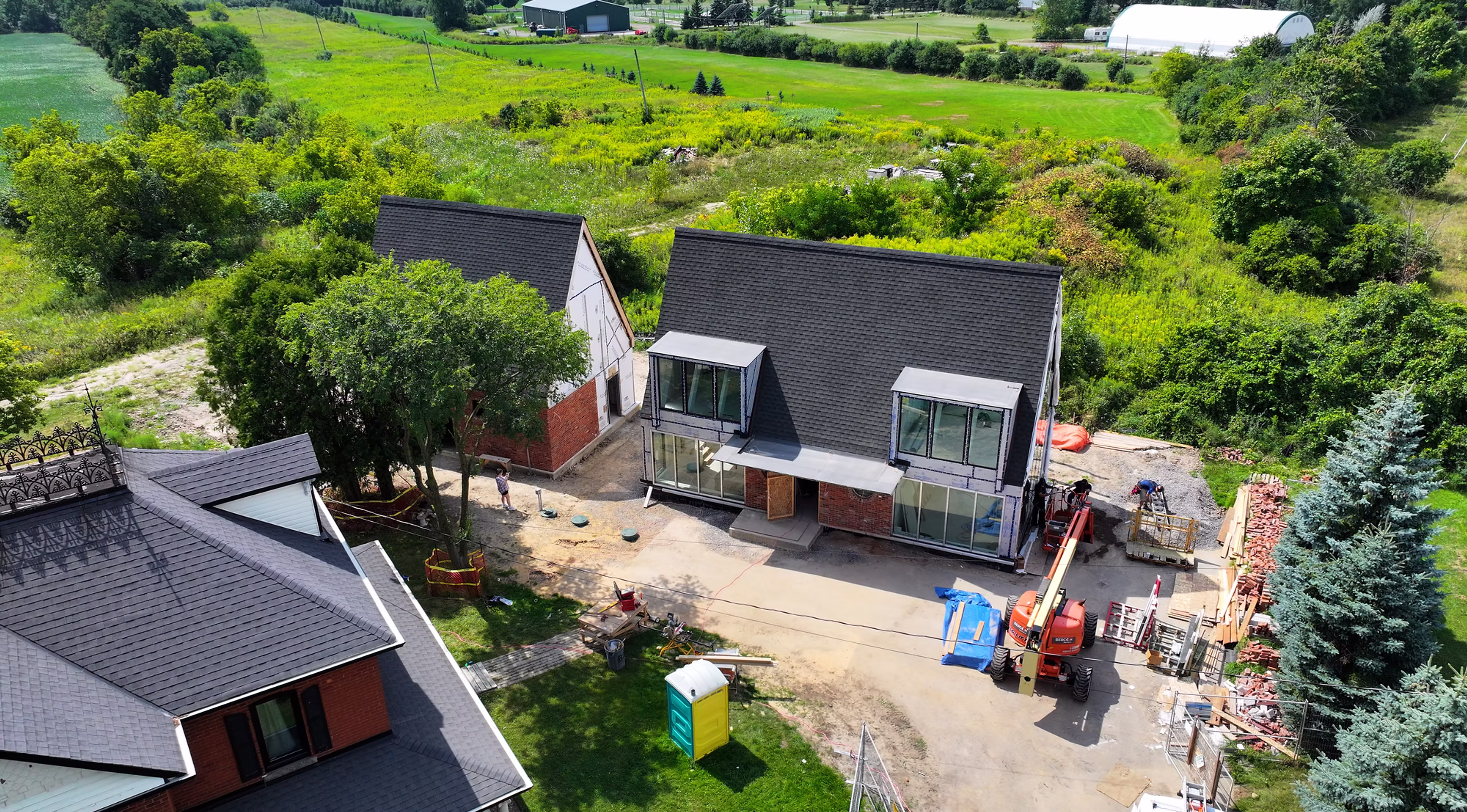 Aerial view of a custom home under construction with dark shingled roofs and large windows by Building Dreams Contracting.