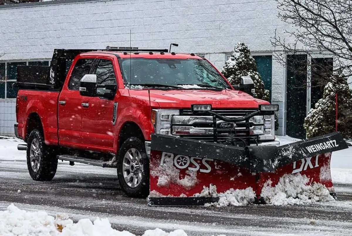 Snow plow truck and snow-removal equipment clearing a parking lot in winter