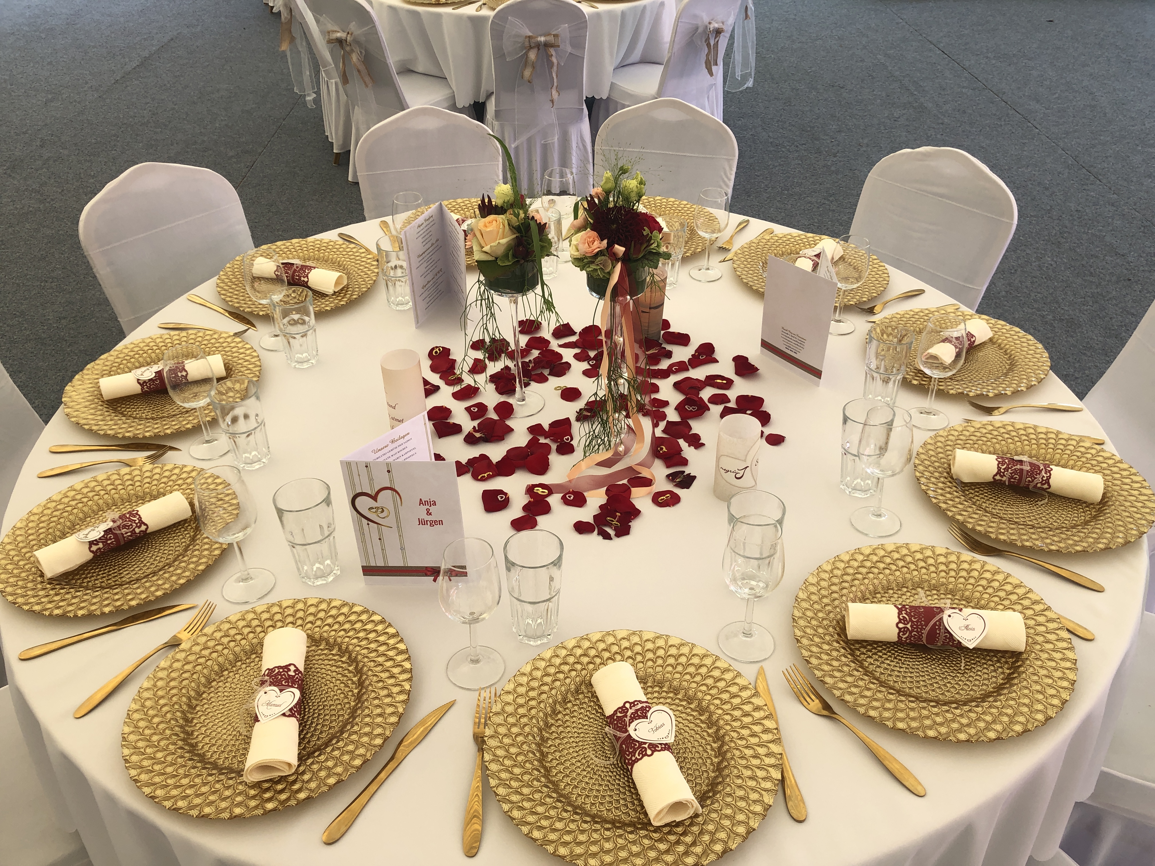 Elegante Hochzeit Tischdekoration mit goldenen Tellern, Rosenblättern und Blumenschmuck bei Flasch City hochzeitslocation near trofaiach