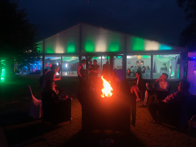 Gäste versammeln sich am Abend um eine Feuerstelle im Außenbereich bei Flasch City hochzeitslocation near Stuhleck