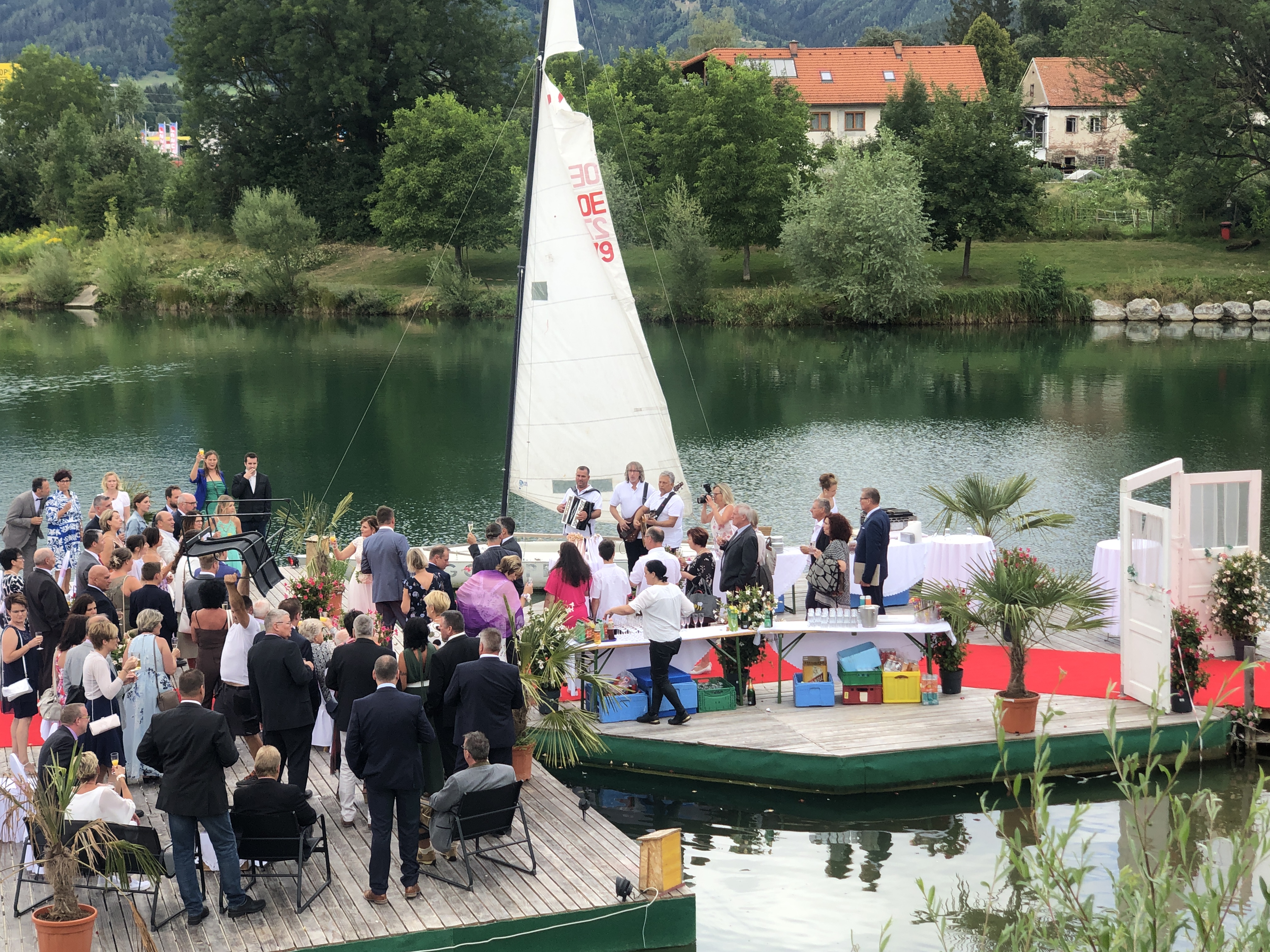 Hochzeitszeremonie mit Gästen auf einem Steg am See mit Segelboot bei Flasch City hochzeitslocation near Weiz