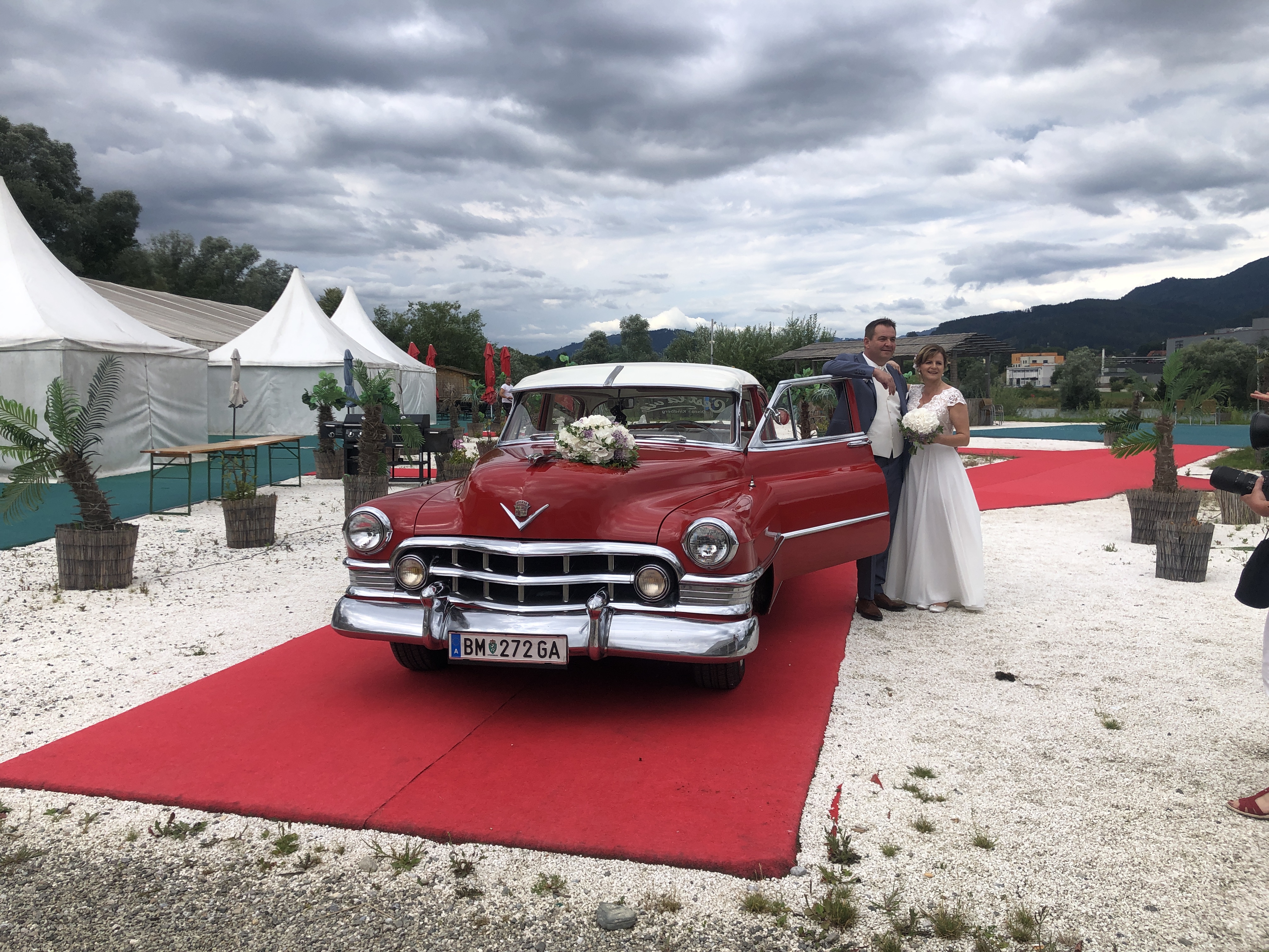 Brautpaar kommt über den roten Teppich mit Oldtimer bei Flasch City hochzeitslocation near obersteiermark