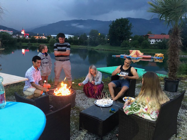 Gäste entspannen an einer Feuerstelle bei Flasch City highway stop near muerzzuschlag am See mit Sitzbereich und Abendstimmung
