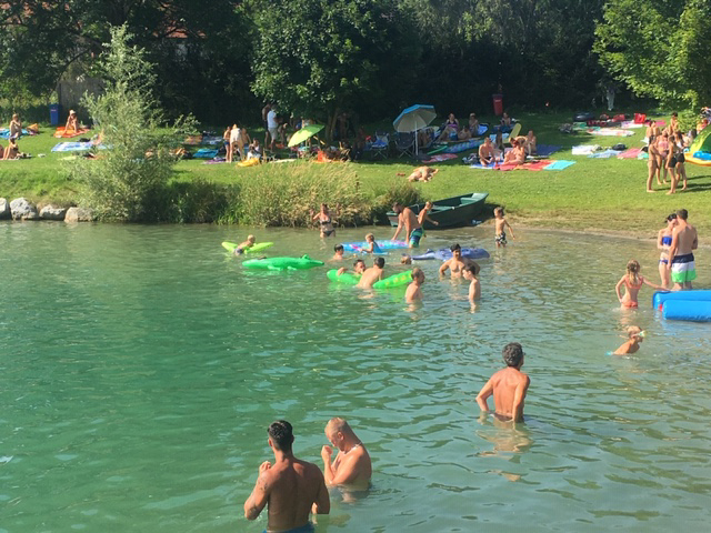Menschen schwimmen und geniessen Wasseraktivitaeten am Badesee bei Flasch City near Wiener Neustadt mit Liegeflaechen entlang des Ufers
