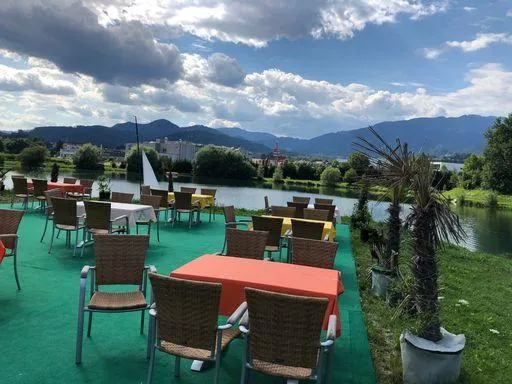 Sitzbereich der Restaurant-Cafe Anlage am Badesee bei Flasch City near Wien mit Blick auf den See und die umliegende Berglandschaft