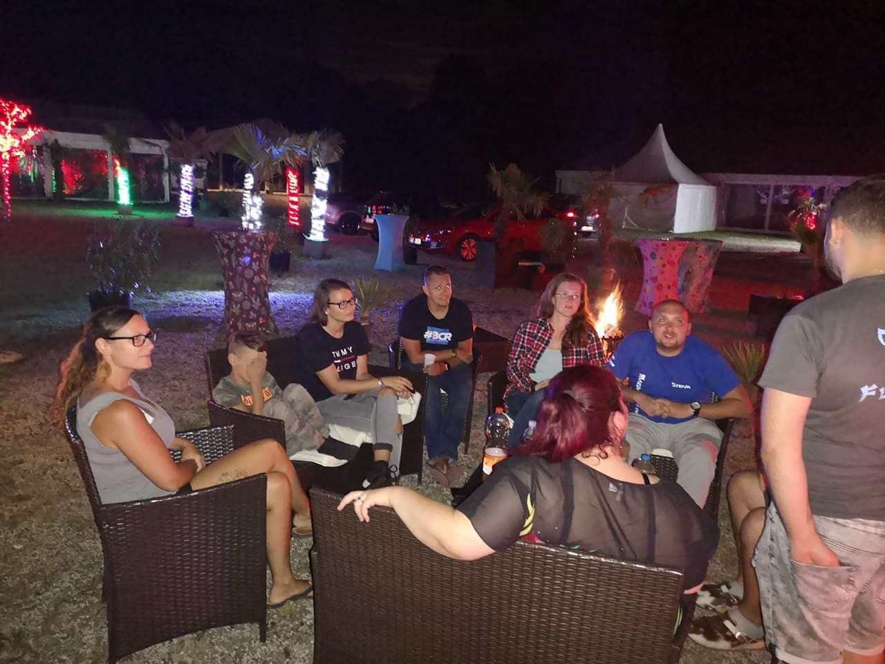Gaeste entspannen am Abend an einer Feuerstelle im Flasch City Restaurant-Cafe near Leoben und geniessen die Atmosphaere mit Speisen zum Mitnehmen