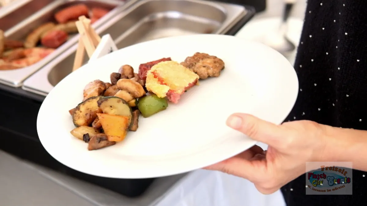 Gast waehlt Fruehstueck vom Buffet mit Gemuese und Fleisch auf einem Teller im Flasch City restaurant-cafe nahe Steiermark