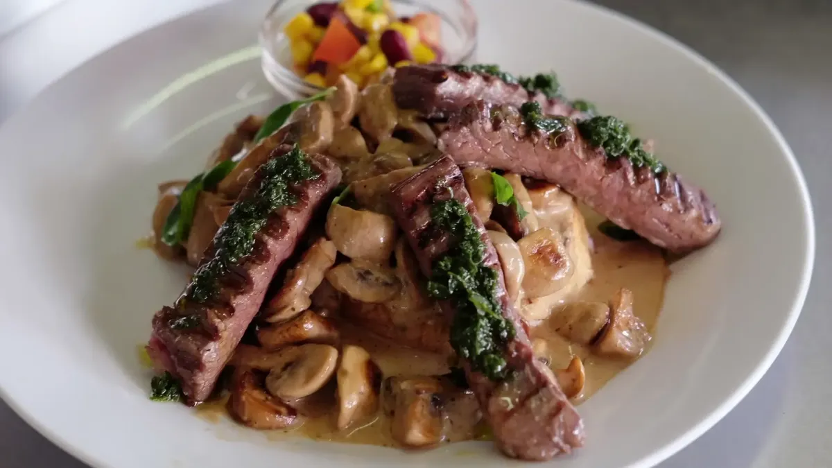 Geschnittenes medium-rare Steak mit Pilzrahmsauce als angerichtetes Gericht im Flasch City steak restaurant-cafe near obersteiermark