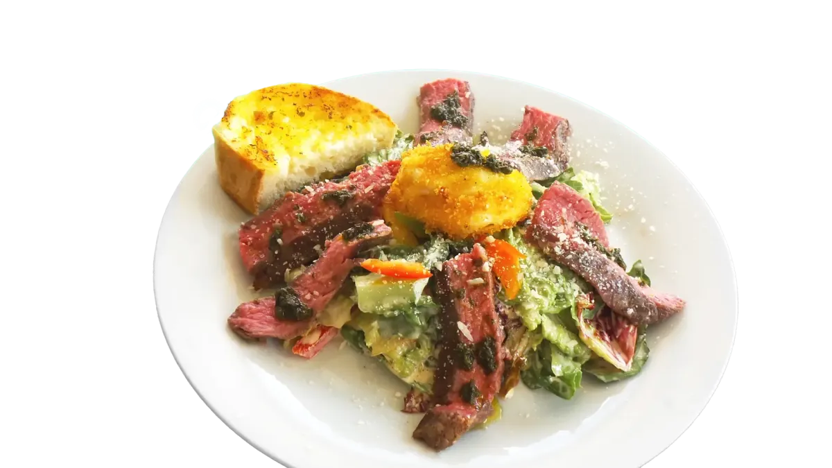 Geschnittenes medium-rare Steak auf frischem Salat mit gebackenem Käse und Brot im Flasch City steak restaurant-cafe near gloggnitz