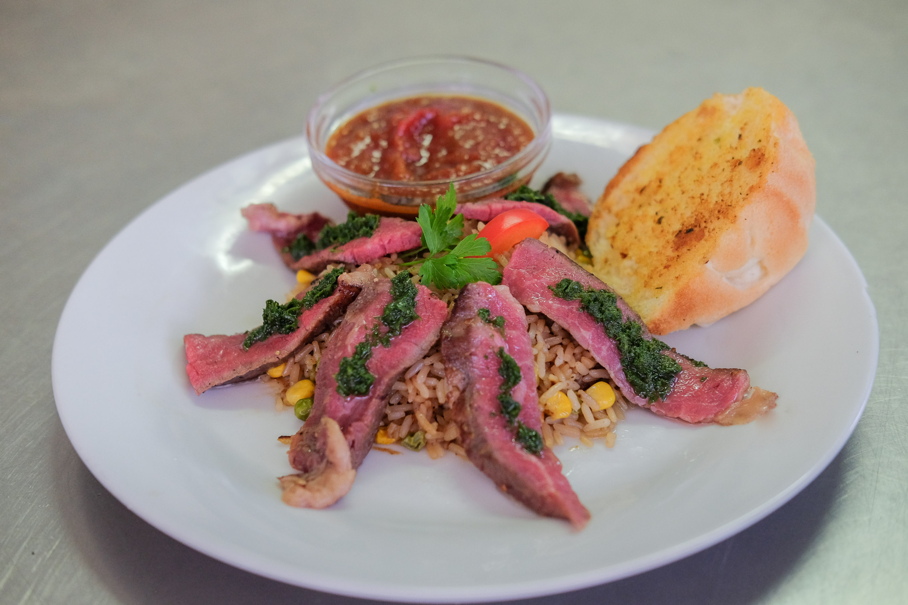 Geschnittenes medium-rare Steak mit Reis und Kräutersauce im Flasch City steak restaurant-cafe near graz