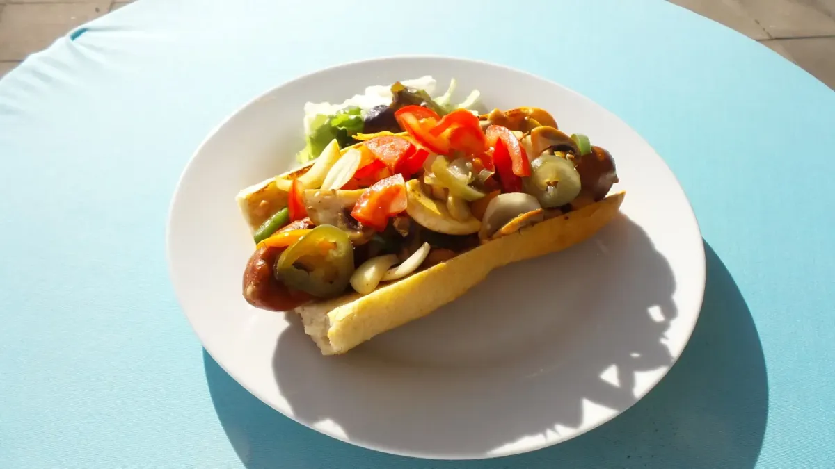 Hotdog mit Wurst, gebratenem Gemüse, Paprika und Jalapeños im Restaurant-Café für Reisebusse & große Gruppen in Flasch City near bruck-an-der-mur