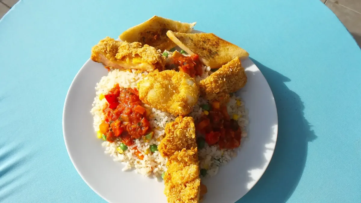 Knuspriger panierter Fisch mit Reis, Gemüse und Tomatensauce im Restaurant-Café für Reisebusse & große Gruppen in Flasch City near st-lorenzen-im-muerztal
