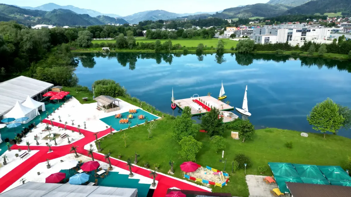 Drohnenaufnahme vom Eventbereich am See mit Steg, Segelbooten und roten Wegen in der Flasch City Eventlocation near Gloggnitz