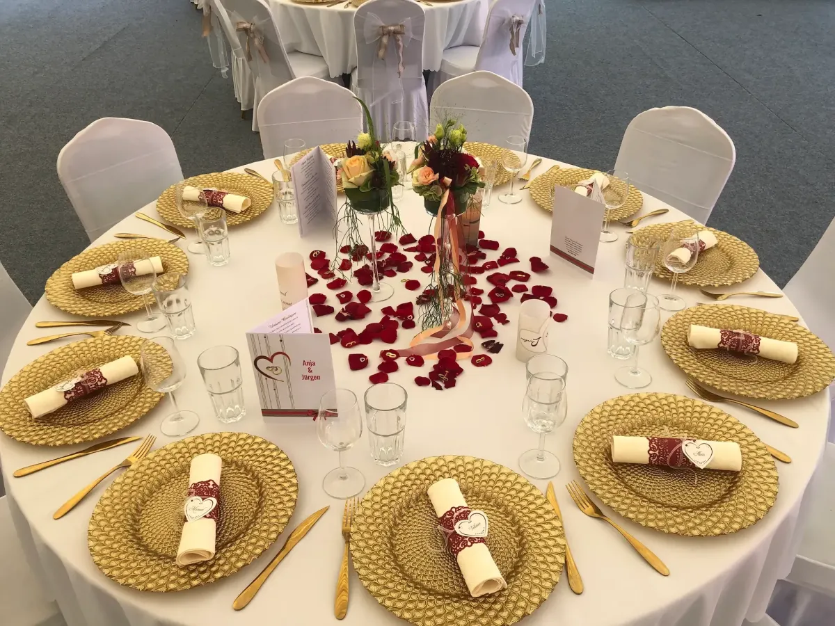 Elegante Hochzeit Tischdekoration mit goldenen Tellern, Rosenblättern und Blumenschmuck bei Flasch City hochzeitslocation