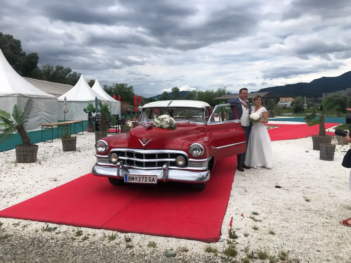 Brautpaar kommt über den roten Teppich mit Oldtimer bei Flasch City hochzeitslocation