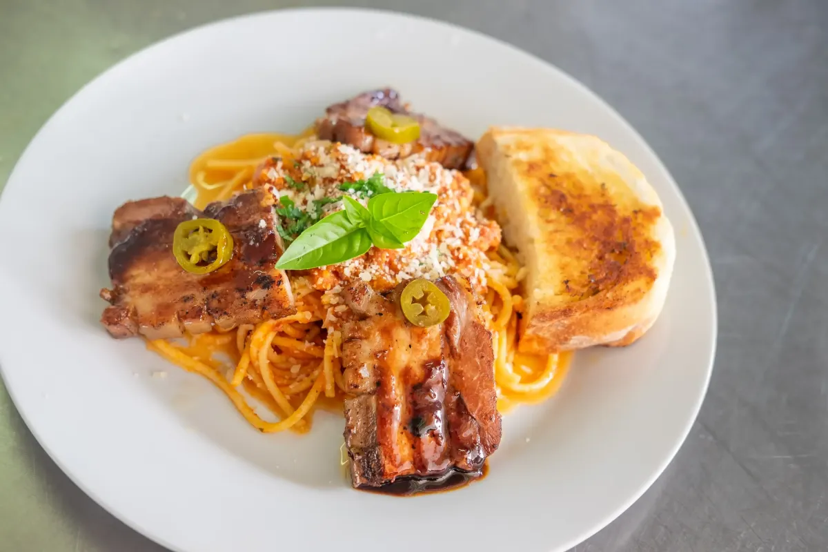 Spaghetti mit gegrilltem Schweinebauch, Parmesan und Knoblauchbrot im Flasch City italienischen Pasta Restaurant-Café leoben