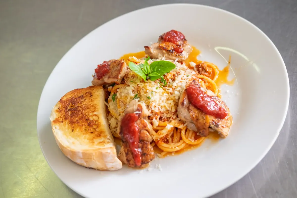 Spaghetti mit gegrilltem Huhn, Tomatensauce, Parmesan und Knoblauchbrot im Flasch City italienischen Pasta Restaurant-Cafe krieglach