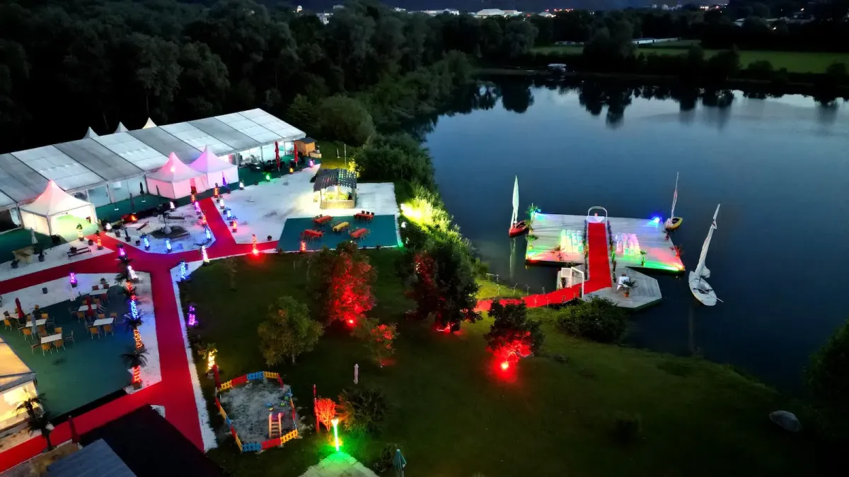 Flasch City italienisches Pasta Restaurant-Café bei Nacht mit beleuchteten Zelten, rotem Teppich und Seeblick