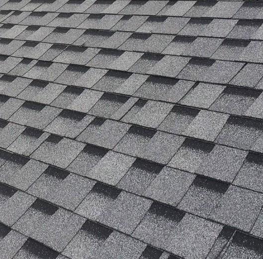Roof repair and maintenance project showcasing a gray house with a completed, durable asphalt roof