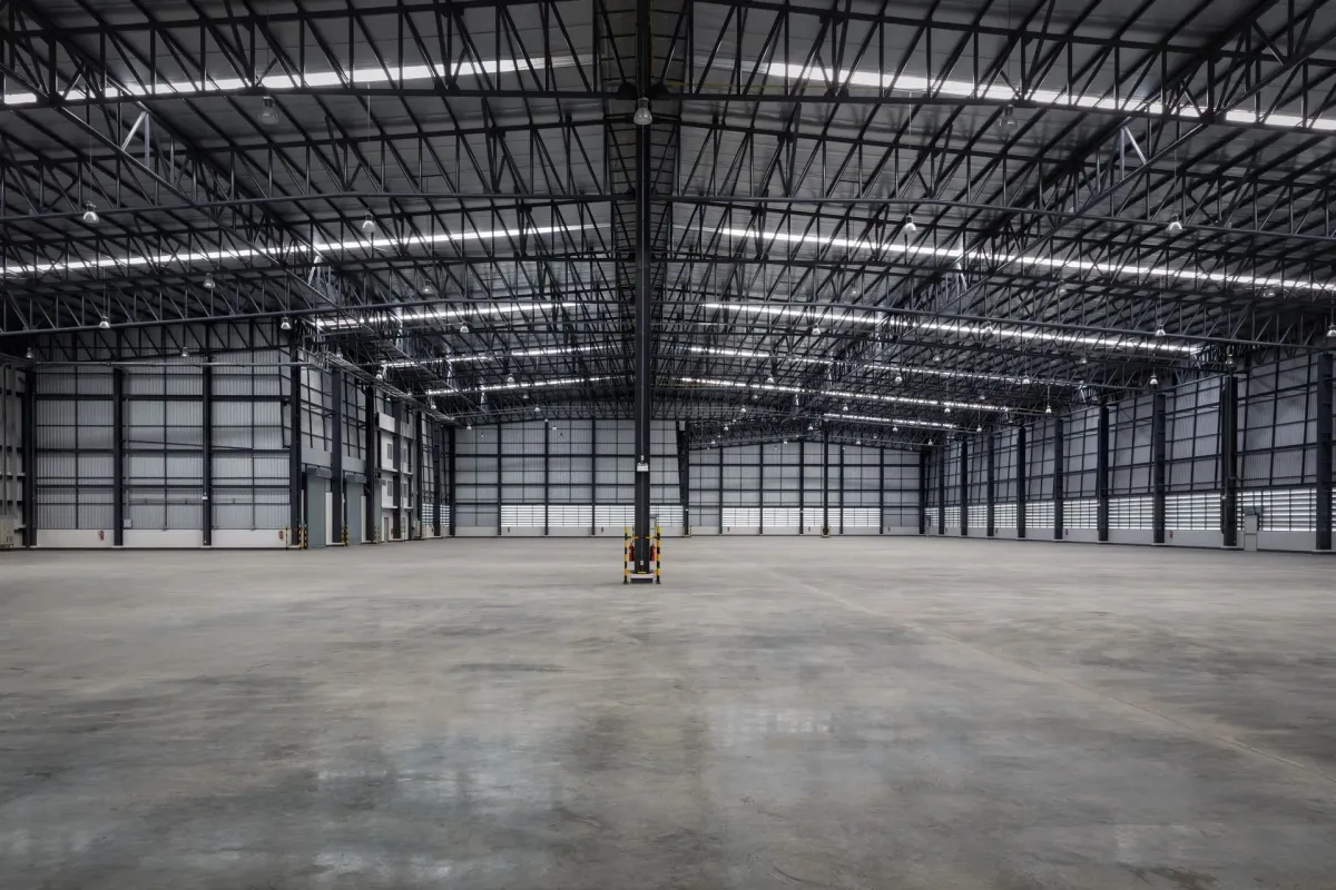 Spacious empty warehouse interior with high ceilings and concrete flooring.