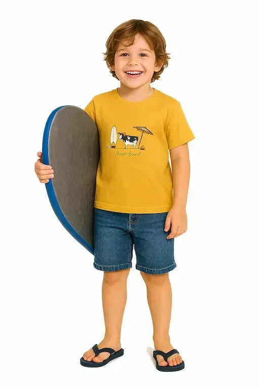 Smiling child in yellow "Beach Bound" t-shirt with cow graphic, denim shorts, and flip-flops, holding a boogie board; toddler clothing.