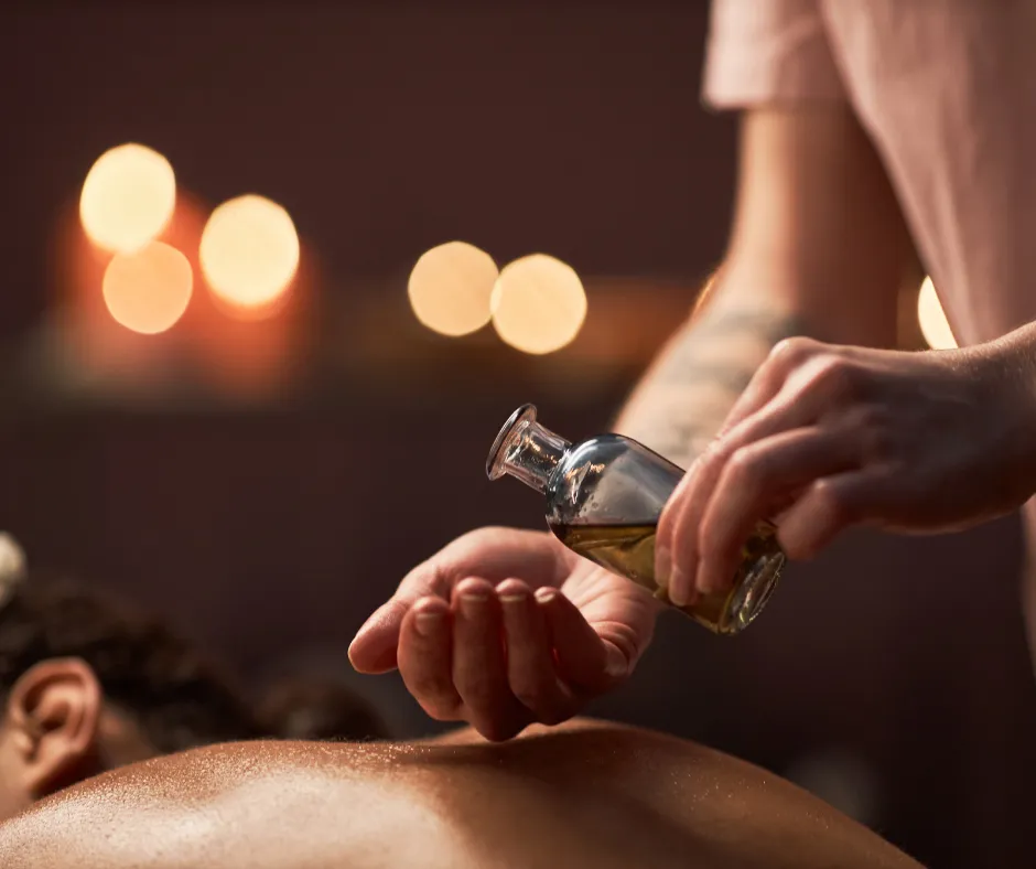 Massage therapist applying essential oils along a client’s spine during a calming aromatherapy treatment.