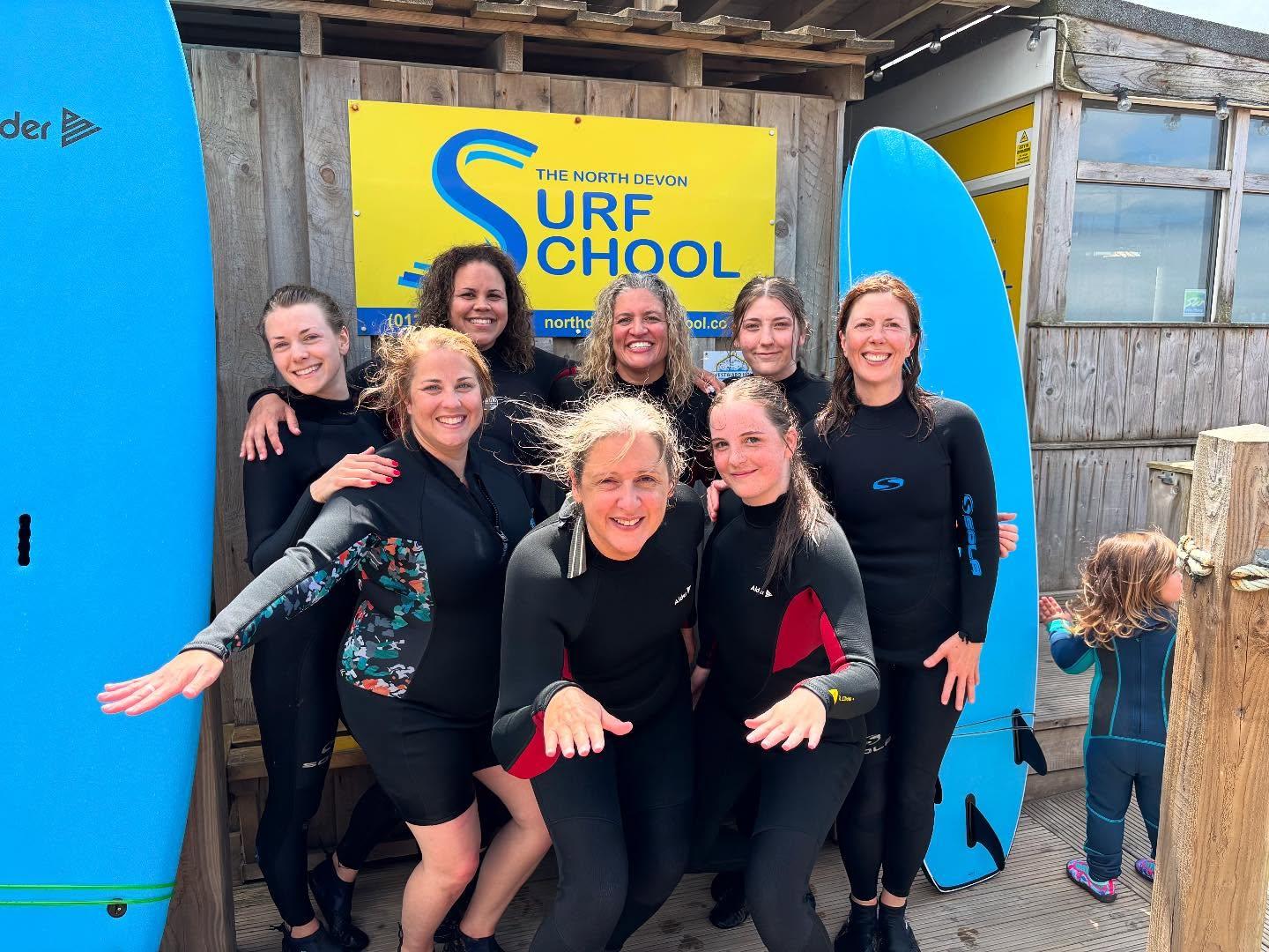 Smiling women in wetsuits with surfboards on the beach