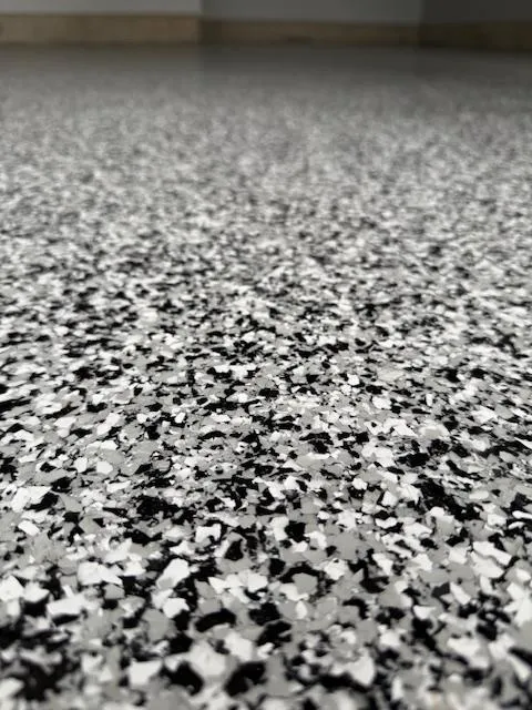 A modern random flake epoxy floor featuring a sparse broadcast pattern that utilizes negative space to highlight a clean, solid base color.
