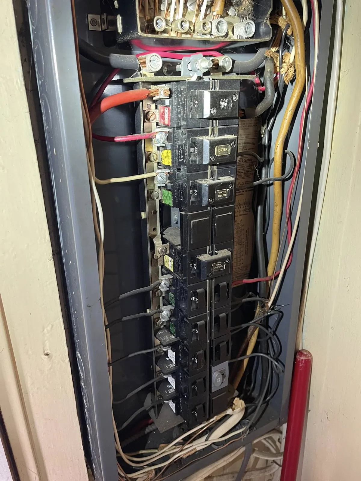 Interior of an older electrical panel showing breakers and existing wiring